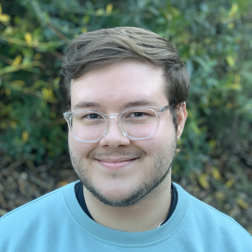 headshot of man with glasses and brown hair with blue shirt
